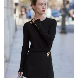 Svart tröja från Zara - Supersnygg svart tröja från Zara med rund hals och lång ärm. Guldknappar på ärmsluten ger en extra touch. Perfekt att styla med kjol eller jeans. Mjuk och skön kvalitet som känns lyxig mot huden.