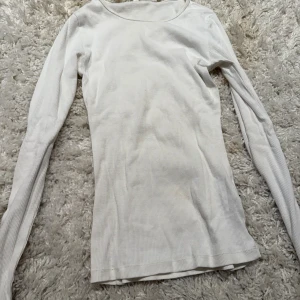 Vit ribbad långärmad tröja H&M XS - En basic vit långärmad tröja från H&M i ribbad bomull. Tröjan har en rund halsringning och sitter tajt mot kroppen, perfekt att styla med jeans eller kjol. Enkel och stilren design som funkar året runt.