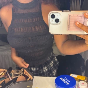 Svart ärmlös spetsklänning - Supersnygg svart topp från free people med hög hals och ärmlös design. Toppen har spets med dekorativa ränder och volanger som ger en trendig look. 