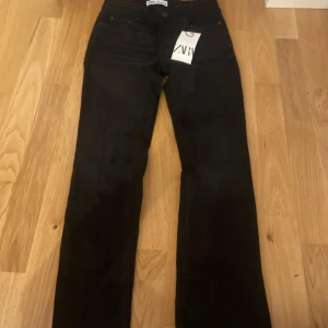 Svarta jeans från Zara, storlek 34 - Svarta jeans från Zara i storlek 34. Klassisk femficksmodell med raka ben och normal passform. Jeansen har hög midja och är tillverkade i ett stretchigt bomullsmaterial för extra komfort. Perfekta till många olika outfits.