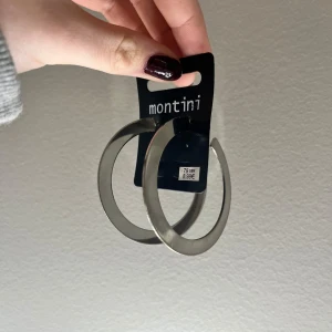 Stora silvriga hoops från Montini - Säljer ett par helt oanvända, stora, runda örhängen i silverfärgad metall från Montini köpta på ur&penn, prislapp kvar. Klassisk hoop-modell som ger en clean och snygg look. Perfekta för att lyfta din outfit med lite extra edge. Diameter ca 6 cm. Så fina nu till hösten🤩