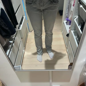 Grå raka jeans med fickdetaljer - Snygga grå jeans med raka ben och klassiska fickor både fram och bak. Jeansen har en normal passform och subtila sömdetaljer på bakfickorna. Perfekta för dig som gillar en enkel och stilren look.