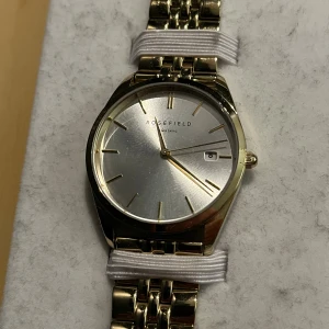 Rosefield klocka nypris 2500kr - Snygg klocka från Rosefield med rund urtavla i silver och guldfärgade detaljer. Länken är guldfärgad och har en klassisk design. Urtavlan har minimalistiska markeringar och datumfunktion. Levereras med originalask och extra länkbitar.
