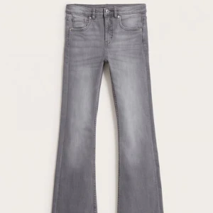 Grå bootcut jeans med utsvängda ben - Snygga grå jeans med bootcut och utsvängda ben. Klassisk femficksmodell med bälteshällor och dragkedjegylf. Jeansen har en tvättad look och är tillverkade i mjukt denimtyg som ger en skön passform.