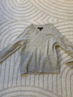 Beige stickad tröja från Amisu - Säljer en beige stickad tröja från Amisu i storlek XS. Tröjan har v-ringad hals, ribbade muddar och lång ärm. Perfekt för lager-på-lager och chill dagar. Materialet är mjukt och skönt mot huden. Ganska så använd men fortfarande fint skick. 