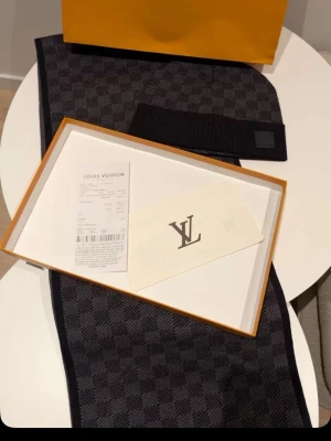 Rutig väst från Louis Vuitton - Säljer en snygg väst från Louis Vuitton i mörkgrått och svart med klassiskt rutigt mönster. Västen har en stilren design och är tillverkad i ett mjukt material som känns lyxigt. Perfekt för dig som vill ha något exklusivt och trendigt.