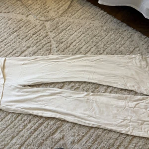 Vita mjukisbyxor från Kappahl - Säljer ett par vita yoga pants från Kappahl i storlek 146. Byxorna har en enkel och slim passform med elastisk midja och är gjorda i mjukt bomullsmaterial. Perfekta för chill dagar hemma eller när du vill vara extra bekväm.