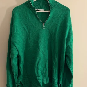 Grön stickad tröja med half zip från Zara - Säljer en grön stickad tröja från Zara i storlek XL. OBS sitter som en (M) Köpt i london 🥰 Tröjan har en ribbad hög krage och en snygg half zip-dragkedja framtill. Modellen är loose fit med långa ärmar och breda ribbade muddar vid nederkant och ärmslut. Perfekt för dig som gillar färg och vill ha en chill look. Den 