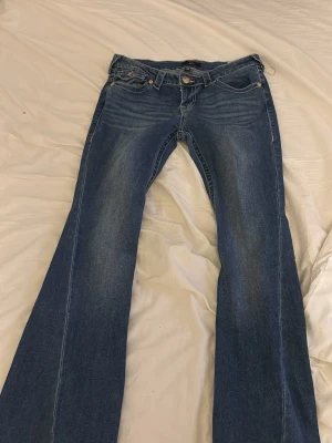 True Religion Joey Low Rise Flare jeans - Pris kan diskuteras.Säljer ett par blå True Religion Joey Low Rise Flare jeans med snygga kontrastsömmar och ikoniska fickor med gul brodering och knappdetaljer. Modellen har låg midja och utsvängda ben, perfekt för dig som gillar retrovibbar och statement-jeans.