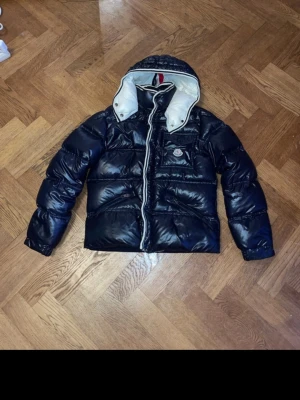 Moncler mörkblå pufferjacka med huva - Säljer en riktigt fin Moncler branson. Jackan är i mycket bra skick och riktigt varm, köpt från vongreven closet och jag har kvitto som jag kan skicka om du är intresserad av att köpa. Den är i barnstorlek xl men passar som xs 165-170. 