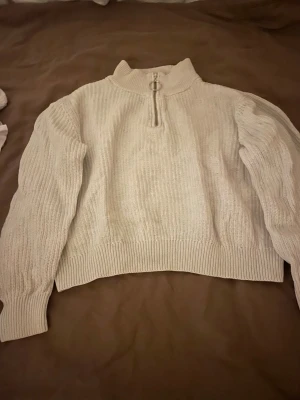 Beige stickad tröja med half zip - Säljer en beige stickad tröja från C i storlek 158/164. Tröjan har en ribbad struktur, hög krage och en snygg half zip med metallring. Perfekt för dig som gillar en enkel men trendig look. Långärmad och loose passform.
