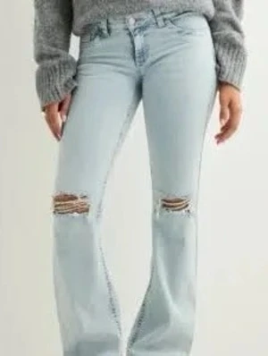 Nelly jeans - Säljer ett par ljusblå jeans med bootcut passform och slitna hål över knäna. Jeansen har väldigt låg midja och hålen är mer slitna än på bilden, säljer bra pris, de är långa och passar bra för mig är 172, men annars kan man sy upp ❤️🥰