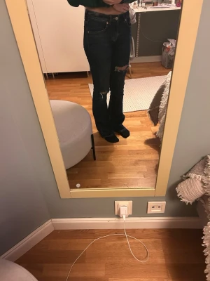 Mörkblå bootcut jeans från lager 157 - Säljer ett par mörkblå bootcut jeans från lager 157 med låg midja. Jeansen har slitningar och hål på benen vilket jag själv lagt till och var inte där när jag köpte. Byxorna är lite slitna längst ner på benet. Längden funkar för mig som är 167cm lång.