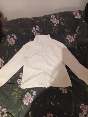 Vit ribbad ziptröja från FB Sister - Säljer en vit ribbad tröja från FB Sister i storlek M. Tröjan har dragkedja framtill, hög krage och långa ärmar med tumhål. Perfekt för lager-på-lager och chill dagar. Den har en lite kortare passform