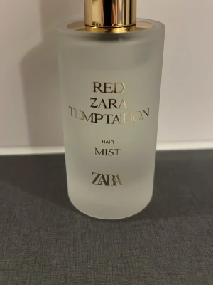 ZARA Red Temptation Hair Mist - ZARA Red Temptation Hair Mist i en frostad glasflaska med gulddetaljer. Doftmisten ger håret en fräsch och lyxig känsla. Flaskan har elegant design och rymmer en lätt, fräsch doft som passar perfekt för att fräscha upp håret under dagen.