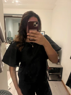 Svart blus med puffärm från Vila - Säljer en svart blus från Vila i storlek 40. Blusen har snygga puffärmar och är tillverkad i ett glansigt polyestertyg som ger en lyxig känsla. Perfekt för dig som vill ha en stilren och trendig topp med det lilla extra. Tröjan är endast använd en gång och köpt för några dagar sedan. 