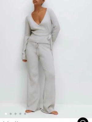 Ljusgrå ribbade mjukisbyxor med snörning - Superbekväma ljusgrå mjukisbyxor i ribbat material med breda ben och dragsko i midjan. Perfekta för chill dagar hemma eller när du vill vara extra cozy. Byxorna har en loose passform och är tillverkade i ett mjukt stickat tyg.  Byxan nypris 300kr o tröjan 360 men båda för 450kr 