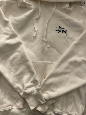 Stüssy hoodie - Vit äkta Stüssy hoodie i storlek S, den är oversized så passar någon som har M/L oxå. Mycket bra skick, använd 2 gånger! Köptes för 2500 kr