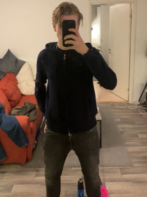 Mörkblå hoodie i kashmir från Sayless - Snygg mörkblå hoodie från Sayless i mjuk kashmir. Tröjan har huva med snörning, dragkedja framtill och två fickor. Perfekt för dig som gillar stilrena och bekväma plagg med lite lyxig känsla. Passar dig som vill ha en hoodie med extra skön kvalitet.