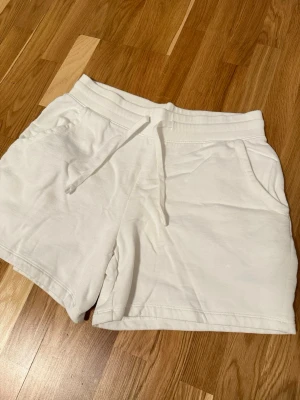 Vita mjuka shorts med snörning - Säljer ett par vita shorts från Cubus i storlek M. De har elastisk midja med snörning, två sidofickor och är gjorda i mjukt bomullsmaterial. Perfekta för chill dagar och har en clean look som är lätt att matcha med hoodies eller t-shirts.