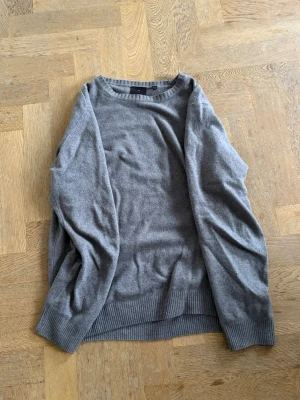 Grå stickad tröja Oscar Jacobson - Mjuk och stilren grå stickad tröja från Oscar Jacobson i storlek M. Tröjan har rund halsringning, ribbade muddar vid ärmslut och nederkant samt lång ärm. Perfekt för lager på lager under kyliga dagar. Pris kan diskuteras vid snabb affär 