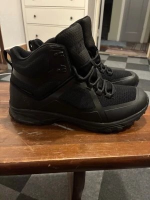 Svarta kängor med grov sula från Urberg - Säljer ett par svarta kängor från Urberg med grov Vibram-sula och snörning. Ovandelen är i slitstark syntet och mesh för bra andningsförmåga. Skorna har hög modell för extra stöd och en modern, sportig look. Använda ett fåtal gånger. Små i storleken. 