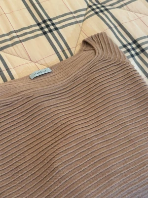 Beige ribbad tröja från Marella - Säljer en beige ribbad tröja från Marella med rund hals och långa ärmar. Tröjan har ett snyggt horisontellt ribbmönster och breda muddar vid ärmslut och nederkant. Perfekt för dig som gillar stilrena och bekväma plagg.