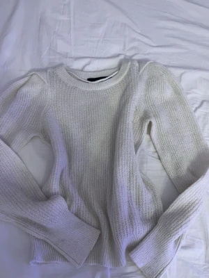 Vit stickad tröja från Vero Moda - Snygg vit stickad tröja från Vero Moda med rund halsringning och långa ärmar. Tröjan har en klassisk ribbstickad struktur och breda muddar vid ärmslut och nederkant. Perfekt för lager på lager och enkel att matcha med allt.