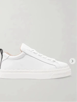 Vita sneakers från Chloé med vågig sula - Stilrena vita sneakers från Chloé med signaturvågig sula och svart dragflik med logga bak. Skorna har en låg profil, vita snören och detaljer i läder. Perfekta för en clean och modern look. Nypris ligger på ca 6000 och de är knappast använda då jag köpte en för liten storlek.🥰