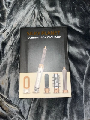 Silky Planet Curling Iron Cloudair - Multifunktionellt stylingverktyg från Silky Planet med flera utbytbara borst- och locktillbehör. Setet är i vitt och guld med svart sladd och passar för olika hårstylingar. Kommer i originalförpackning och innehåller flera delar för flexibel användning.