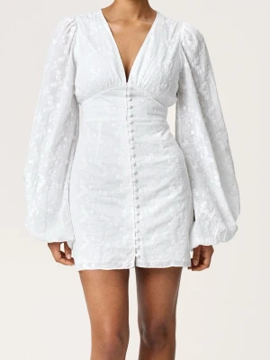 Vit kort klänning med puffärm Adoore  - Kort vit klänning med v-ringning, puffiga långärmar och knappar framtill. Klänningen har broderade blommor i tyget och markerad midja för en feminin siluett. Perfekt för sommarens alla tillfällen. Från adoore. Intressekoll 