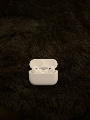 Apple AirPods Pro trådlösa hörlurar - Säljer ett par vita Apple AirPods Pro med laddningsetui. De är trådlösa in-ear hörlurar med stilren och kompakt design i plast. Perfekta för musik, samtal och smidig anslutning till iPhone. Laddningsfodralet är också vitt och har en magnetisk stängning.