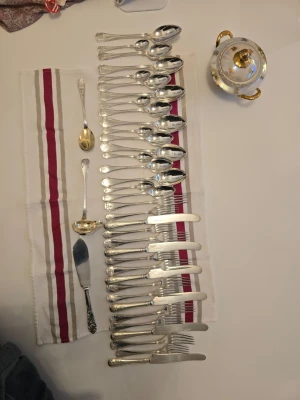 Vackert vintage Bestickset extra Prima NS 40. - Säljer ett stort set silverfärgade besticksett med klassiskt graverat mönster på handtagen. Setet innehåller 6 knivar, dessertknivar,  gafflar, dessertgafflar, matskedar, dessertskedar,teskedar, en såsslev, en serveringssked och en tårtspade. Allt i metall och elegant design för snygg dukning.