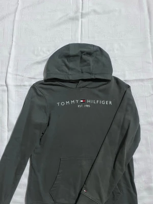 Grön Tommy Hilfiger Hoodie   - En mörkgrön hoodie som passar både för henne och honom, det kan vara en bra present till dina yngre. Den är luftig och ganska lös inte för tajt. Fortfarande i bra form och priset kan diskuteras💚