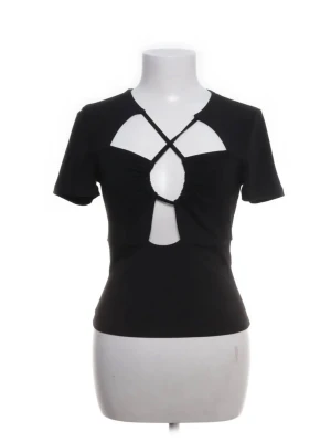 Svart topp med cut out från Bik Bok - Säljer en svart topp från Bik Bok med korta ärmar och snygga cut out-detaljer framtill. Tröjan är i storlek M men jag som vanligtvis använder toppar i storleken S kan ha tröjan utan problem så tröjan är liten i storlek 💞💞