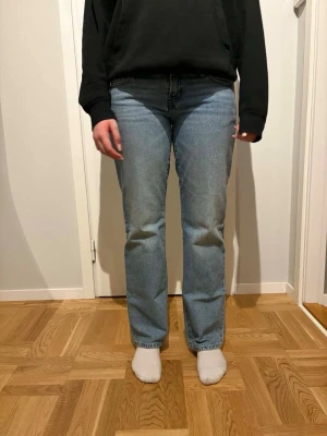Ljusblå raka jeans i bomull - Säljer ett par ljusblå jeans med rak passform och klassisk femficksdesign. Jeansen har normalhög midja och är tillverkade i mjuk bomull. Perfekta för en avslappnad och stilren look.