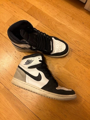 Air Jordan 1 Mid – svart/vit/grå - Säljer ett par Air Jordan 1 Mid i svart/vitt/grått. Skorna är använda och har synligt slitage, främst på sulan och lätt runt kragen, men är fortfarande fullt användbara. Inga sprickor i sulan eller större skador. Hör gärna av dig vid frågor 😀