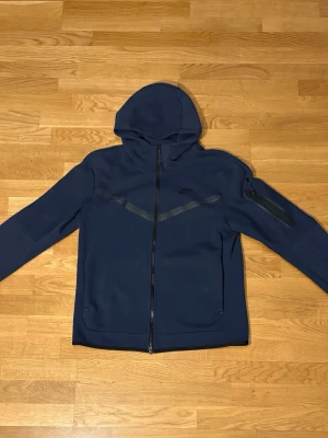 Nike Tech Fleece – mörkblå, i gott skick! - Knappt använd, mjuk och bekväm – perfekt för både vardag och träning. Säljs som helt set: 900 kr, eller separat: hoodie 600kr / byxor 500 kr. Snabb affär går bra!