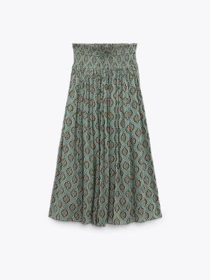 Grön mönstrad långkjol med smock - Säljer en grön långkjol med smock i midjan och ett snyggt retroinspirerat mönster. Kjolen har en avslappnad passform och är gjord i ett lätt och luftigt material, perfekt för varmare dagar. Passar till både sneakers och sandaler.