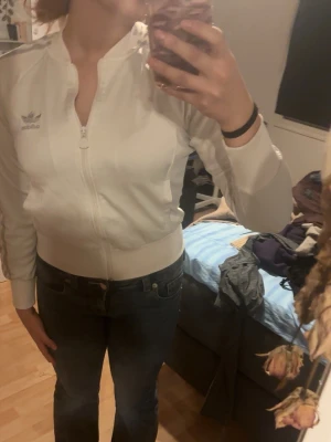 Vit Adidas ziptröja med ränder - Säljer en vit ziptröja från Adidas med klassiska tre ränder i silvergrått längs ärmarna och Adidas-logga på bröstet❤️