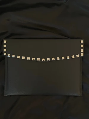 Datorfodral med silvernitar läderimitation  - Förbeställning 7-12  arbetsdagar. Skriv till oss om intresserad!! Rea - endast 199 kr (ord. pris 249 kr)! Stilrent datorfodral tillverkat av veganskt läder i vattentätt material. Fodralet stängs med knapp. Fodralet skyddar din dator effektivt samtidigt som det ger din outfit en extra touch. ⚜️ Storlek: 34 × 25 cm – passar svarta HP Chromebooks och andra datorer i liknande storlek. 