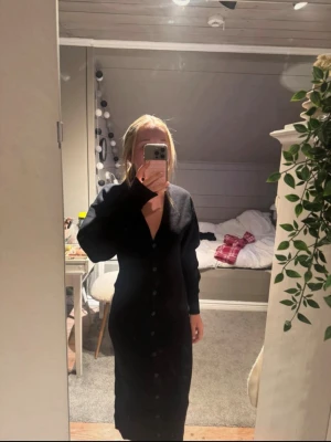 Supersnygg svart långärmad klänning med knappar - Svart stickad långklänning från Gina Tricot med v-ringning och långa ärmar. Klänningen har knappar längs hela framsidan och en figurnära passform. Använd en gång💞     Köpte för 800