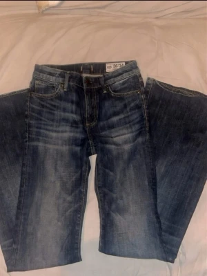 blå jeans bootcut - Säljer ett par klassiska jeans i blå tvätt med bootcut passform. Jeansen har fem fickor, knappgylf och snygga slitningar för en avslappnad look. Perfekta för dig som gillar tidlös denimstil.                                                           Öppen till pris förslag 