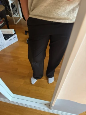 Svarta byxor  - Säljer ett par svarta mjukisbyxor med resår i midjan och raka ben. Byxorna har en enkel och clean look, perfekta för chill dagar. Materialet känns mjukt och bekvämt mot huden. Klassisk svart färg som passar till allt. Låg i midjan skulle jag säga. 