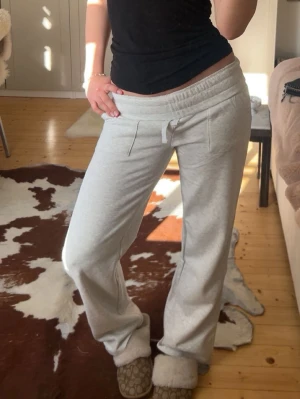 Ljusgrå mjukisbyxor med snörning - Säljer ett par ljusgrå mjukisbyxor med snörning i midjan och raka ben. Byxorna har två fickor fram och är tillverkade i mjukt bomullsmaterial. Perfekta för chill dagar eller när du vill vara extra bekväm. Fittar S-M