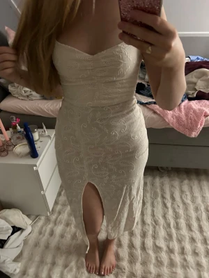 Beige sommarklänning  med slits - Superfin vit långklänning med tunna axelband och snygg slits framtill. Klänningen har broderade detaljer i spets och ett smickrande åtsittande snitt. Öppen rygg med snörning som ger en extra touch. Från Zara. Perfekt för dig som vill sticka ut lite extra! Köp bundle för bästa pris! säljer på Vinted också så skriv till mig innan köp