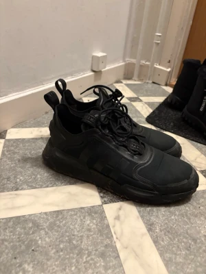  Adidas NMD_V3 sneakers  - Säljer ett par Adidas NMD_V3 i färgen Core Black i storlek EU 45. Skorna är använda men i bra skick och fungerar fint som vardagsskor.  ✔ Populär modell (NMD_V3) ✔ Klassisk svart design ✔ Bekväma och stilrena ✔ Normalt slitage på sulan (se bilder)  Perfekt för dig som vill ha ett par snygga sneakers till vardag eller jobb. Jag snyggar självklart till dom vid eventuell affär!