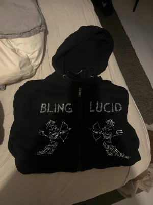 Svart snygg hoddie  - Svart blinglucid hoddie som knappt är använd. Är i storlek s men kan absolut passa m också! Passar både tjejer och killar. Inga defekter på den. Pris kan diskuteras!