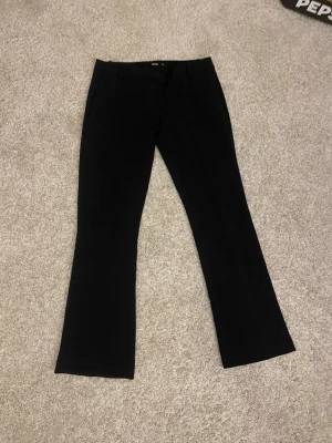 Svarta bootcut kostymbyxor BikBok - Säljer ett par svarta kostymbyxor från BikBok i storlek 40. Byxorna har bootcut-modell med utsvängda ben, bälteshällor och stängs med knapp och dragkedja. Perfekta till en snygg och clean look. De är även lågmidjade och det syns inte att man har använt dem. 