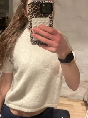 Vit stickad kortärmad tröja  - Mysig vit stickad tröja från Gina Tricot med korta ärmar och rund hals. Tröjan har en boxig, lite loose passform och är perfekt för lager på lager. Superenkel att styla till både jeans och kjol. Andvän 1 gång. 